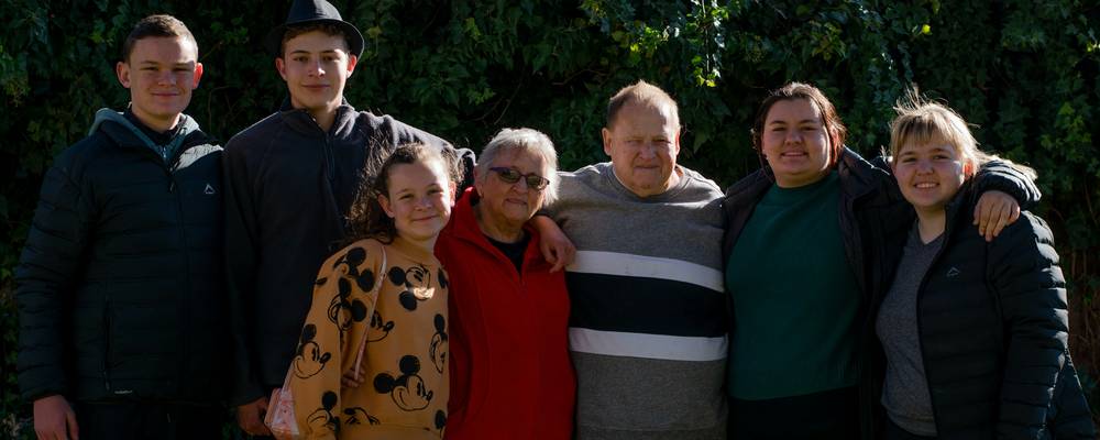 A welcoming Utah family in front of their home, representing community support and welfare assistance.